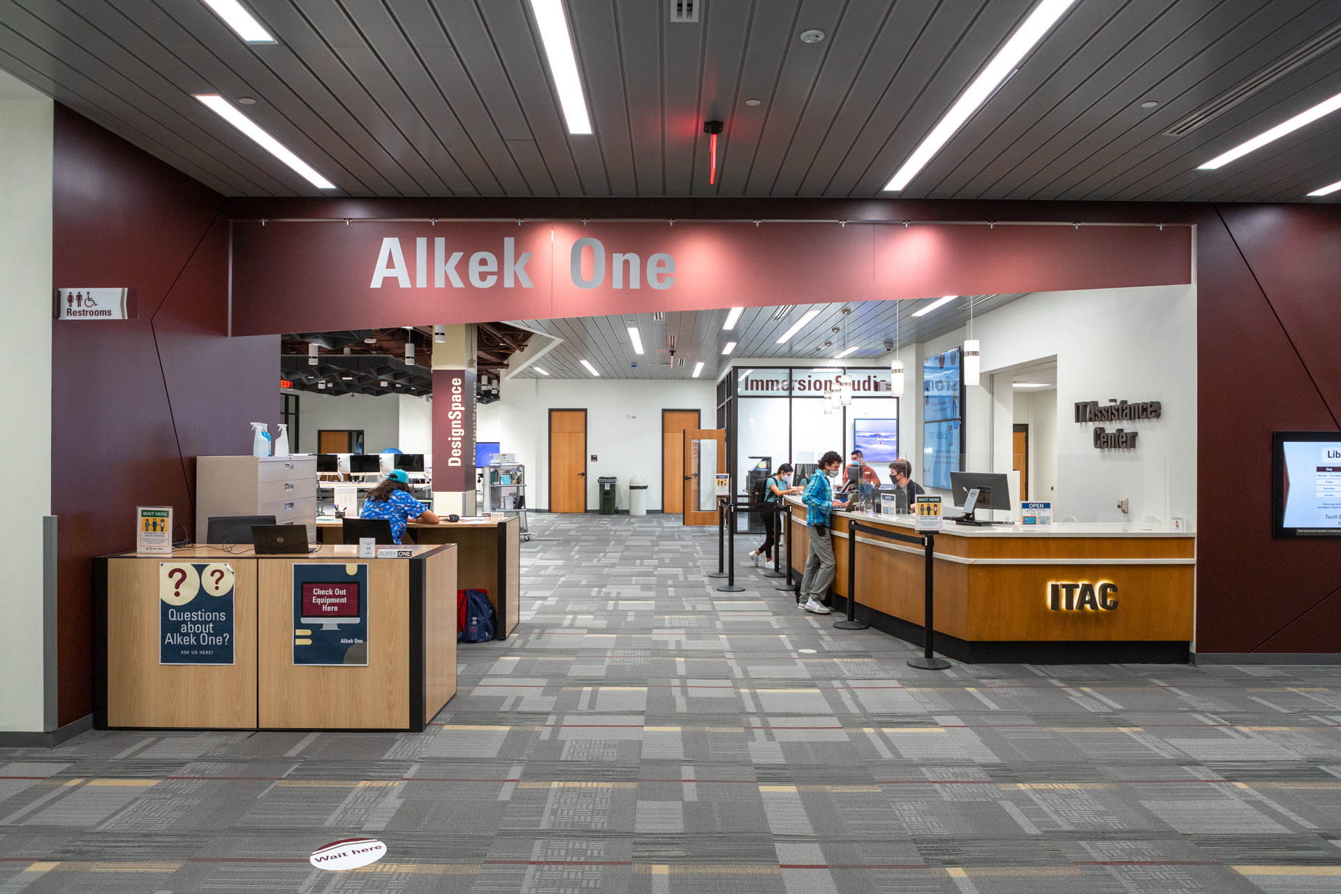 The lobby of Alkek One at Texas State University Libraries featuring some people at a help desk